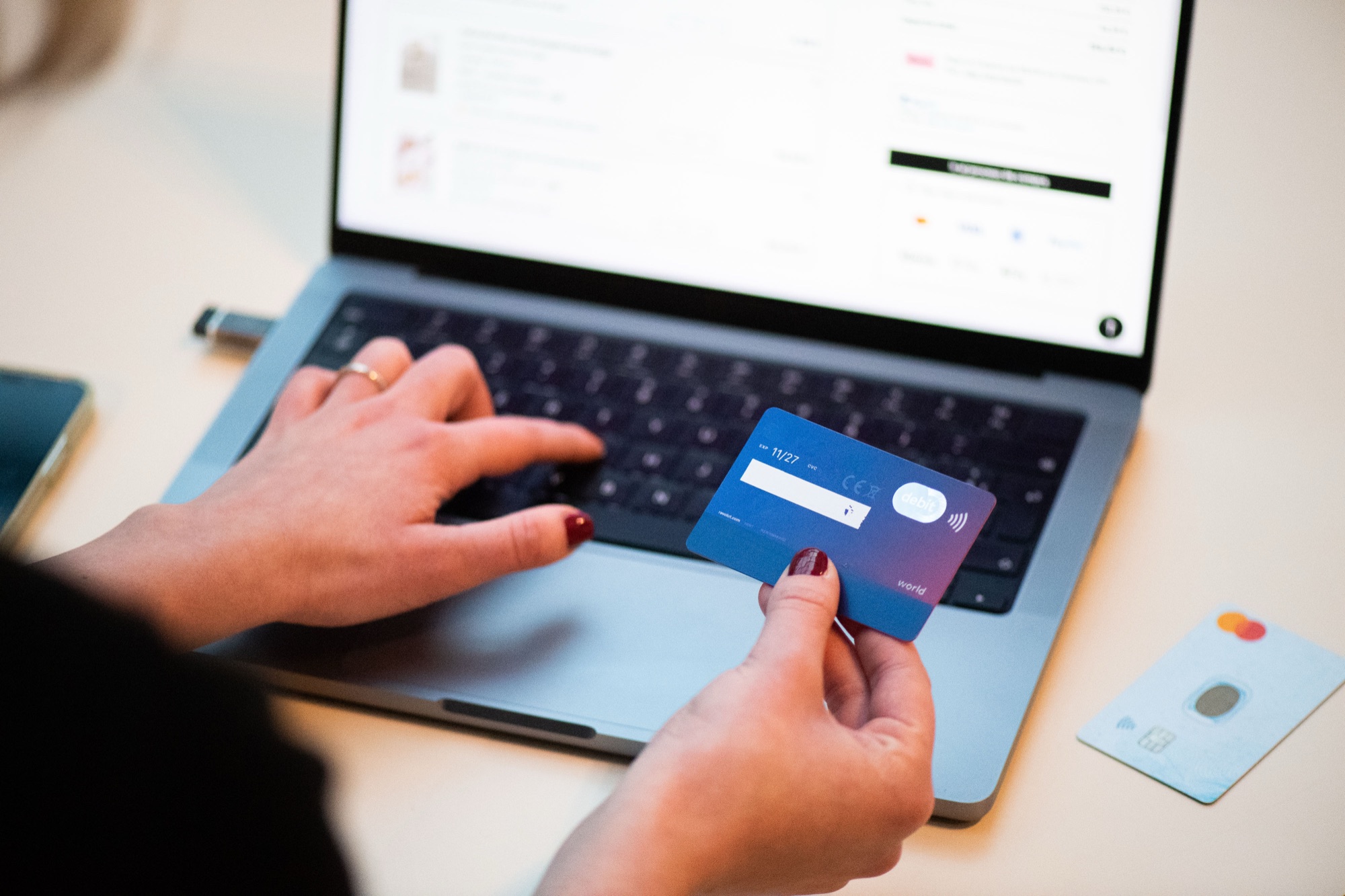 Personne qui règle un achat en ligne avec une carte bancaire devant un ordinateur portable