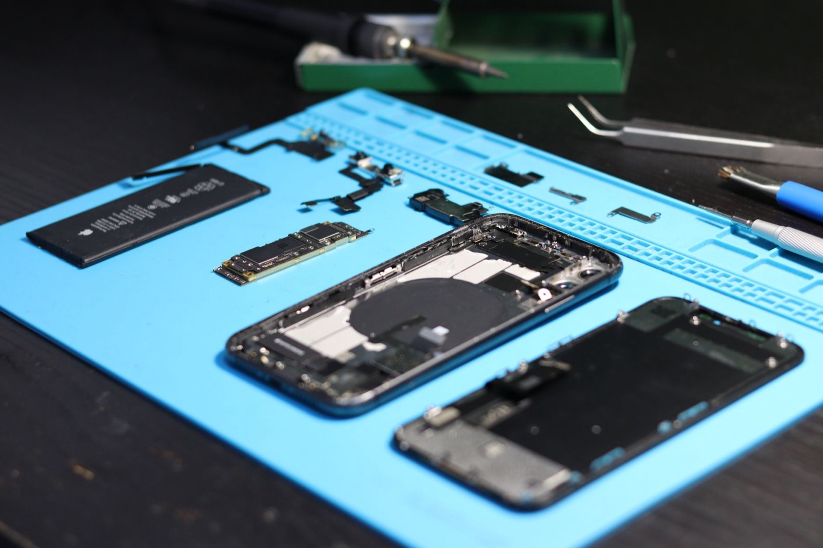 Technicien remplaçant une batterie de smartphone avec des outils de précision