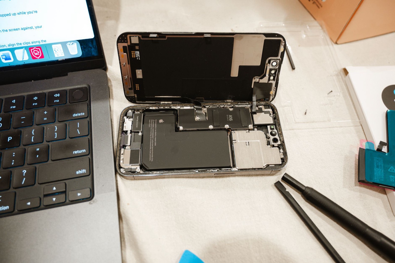 Outils de précision posés à côté d'un téléphone ouvert pour un remplacement de batterie