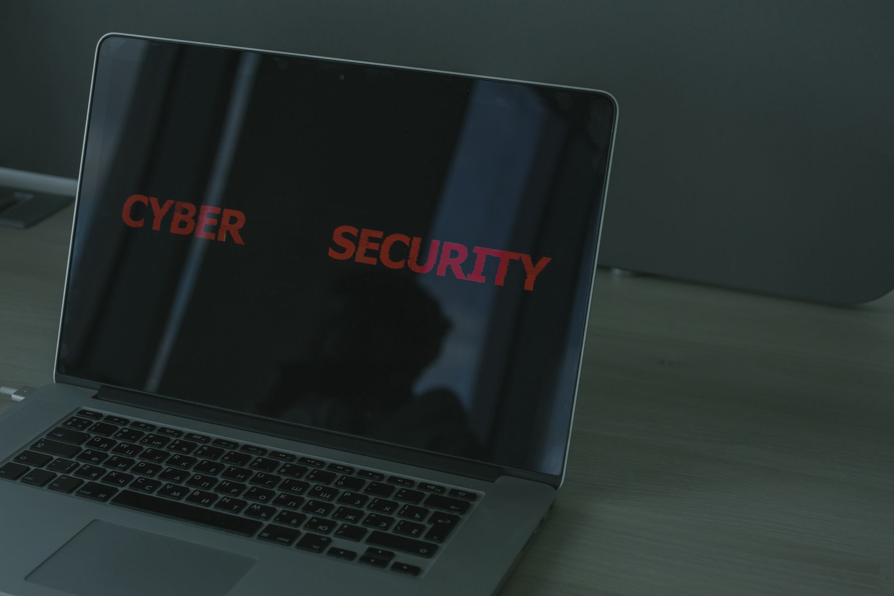 Ordinateur portable ouvert dont l'écran noir affiche les mots Cyber Security en lettres rouges